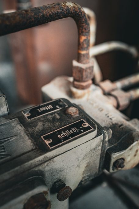 Detailaufnahme eines alten mechanischen Geräts mit Hebeln und verrosteten Rohren.