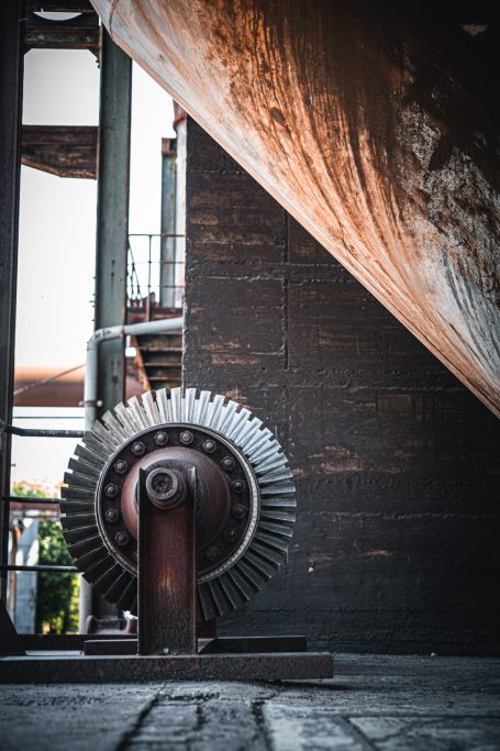 Große metallene Turbine in einer alten Industrieumgebung mit Lichtspiel.