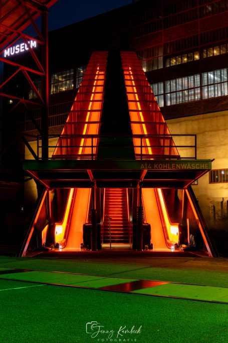 Beleuchtete Treppe mit orangefarbener Illumination in einer urbanen Umgebung bei Nacht.