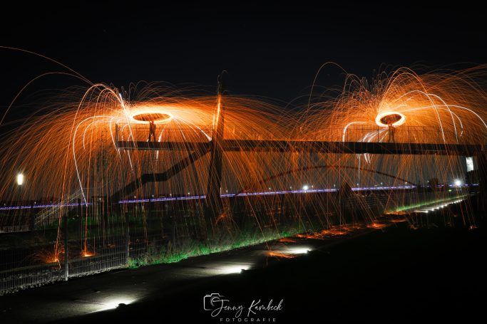 Lange Belichtung einer Brücke mit feurigem Sprüheffekt bei Nacht.