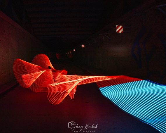 Abstracte Lichtinstallation in einem Tunnel mit roten und blauen Lichtstrahlen.