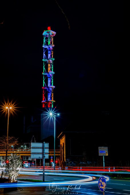 Bunte Lichter erhellen den hohen, spiralförmigen Turm bei Nacht.