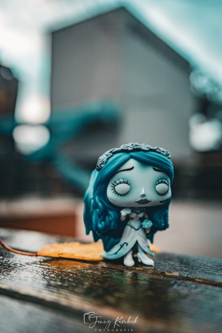 Eine figur einer Braut mit blauen Haaren und einem weißen Kleid, unscharf im Hintergrund.
